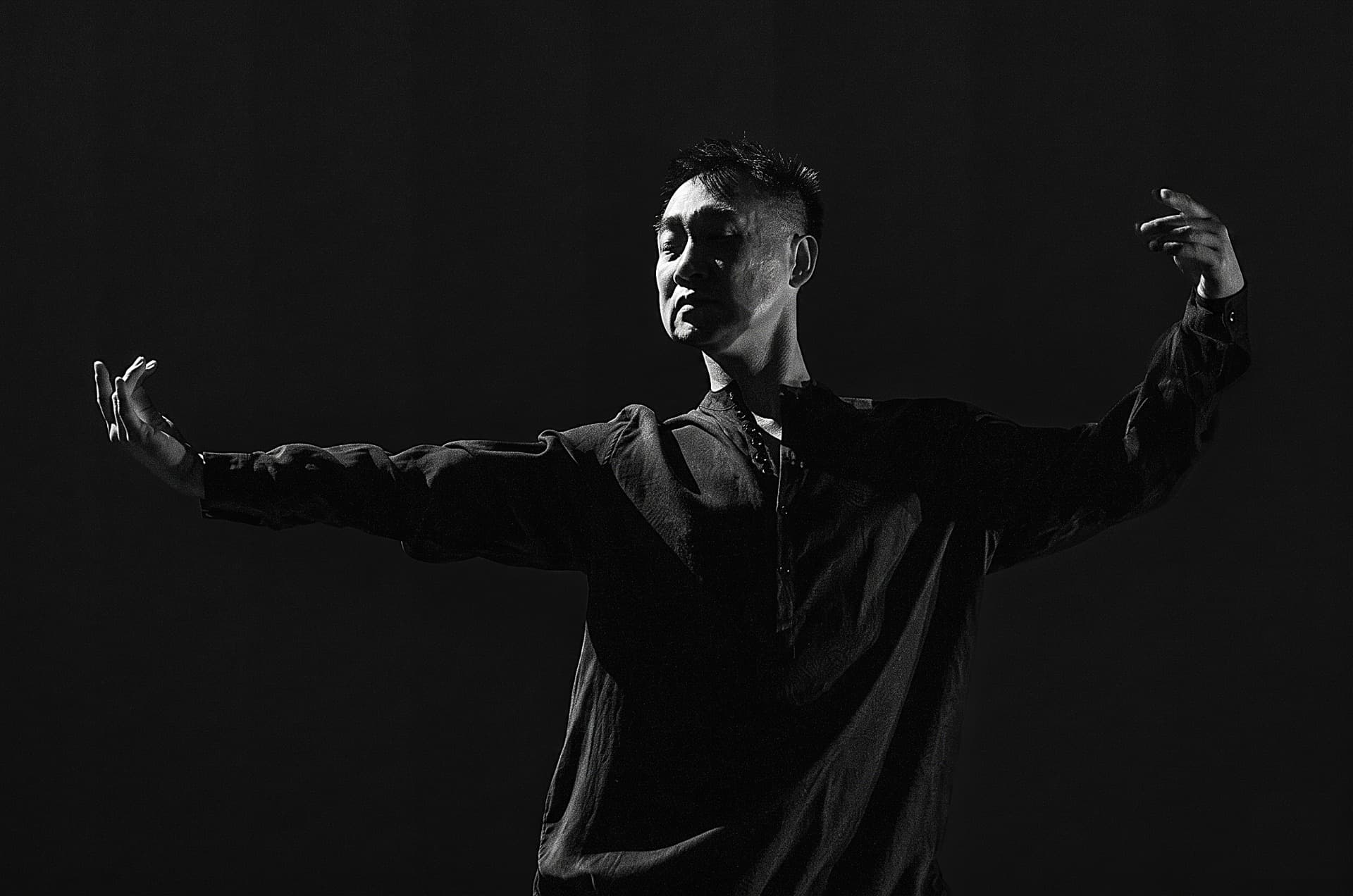 Dancer with arms outstretched in a dramatic spotlight